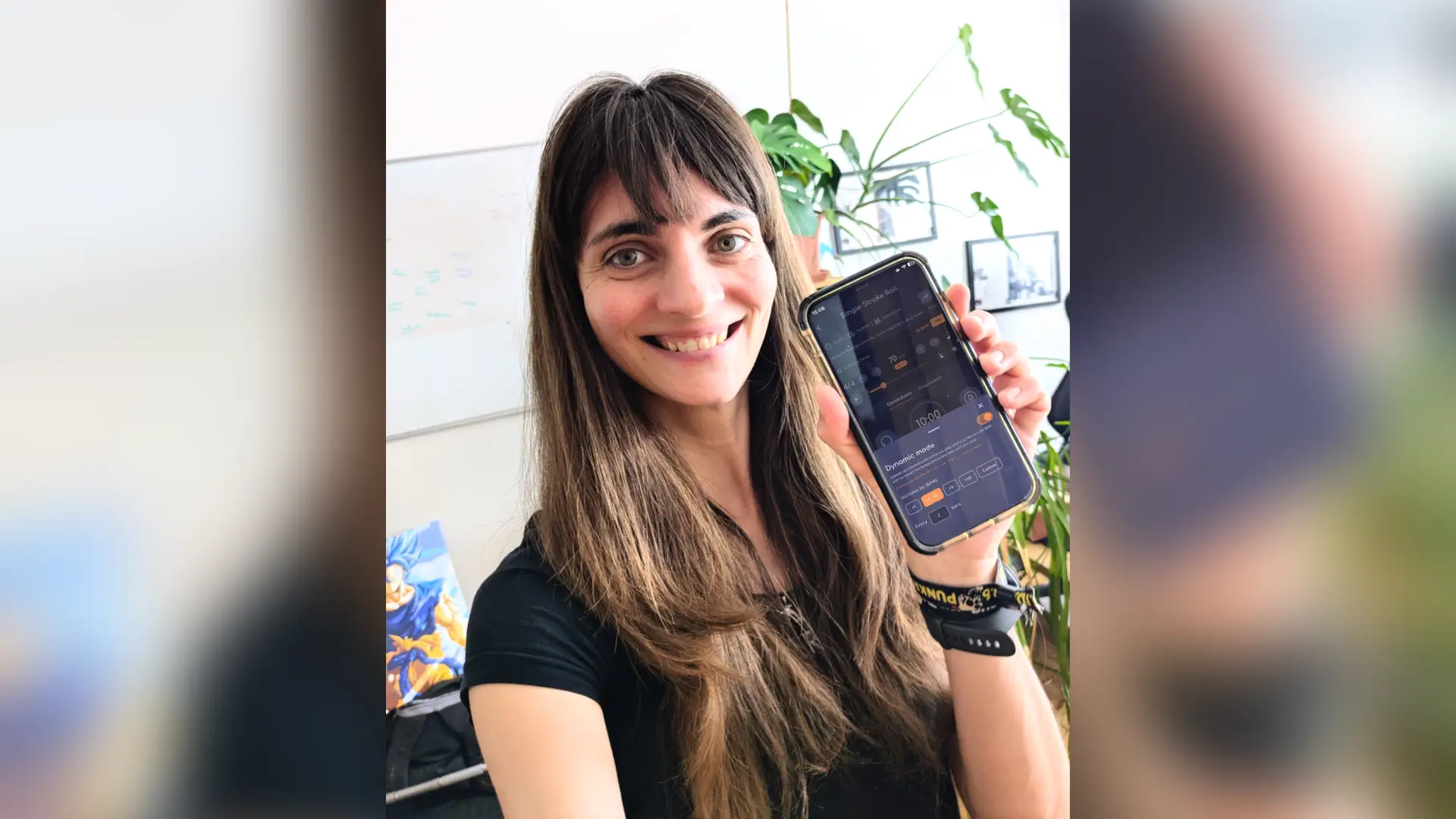 Verena Zaiser holding a phone showing the Drumbitious dynamic metronome with Dynamic mode open